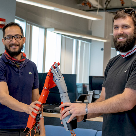 Assistant professor Asheesh Lanba and electrical engineering major Adam Robert high-five using prosthetic arm prototypes they developed in our MIST lab.