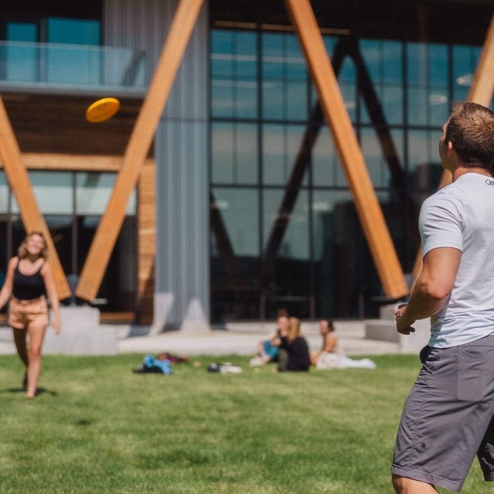 Students playing frisbee in front of McGoldrick Student Center