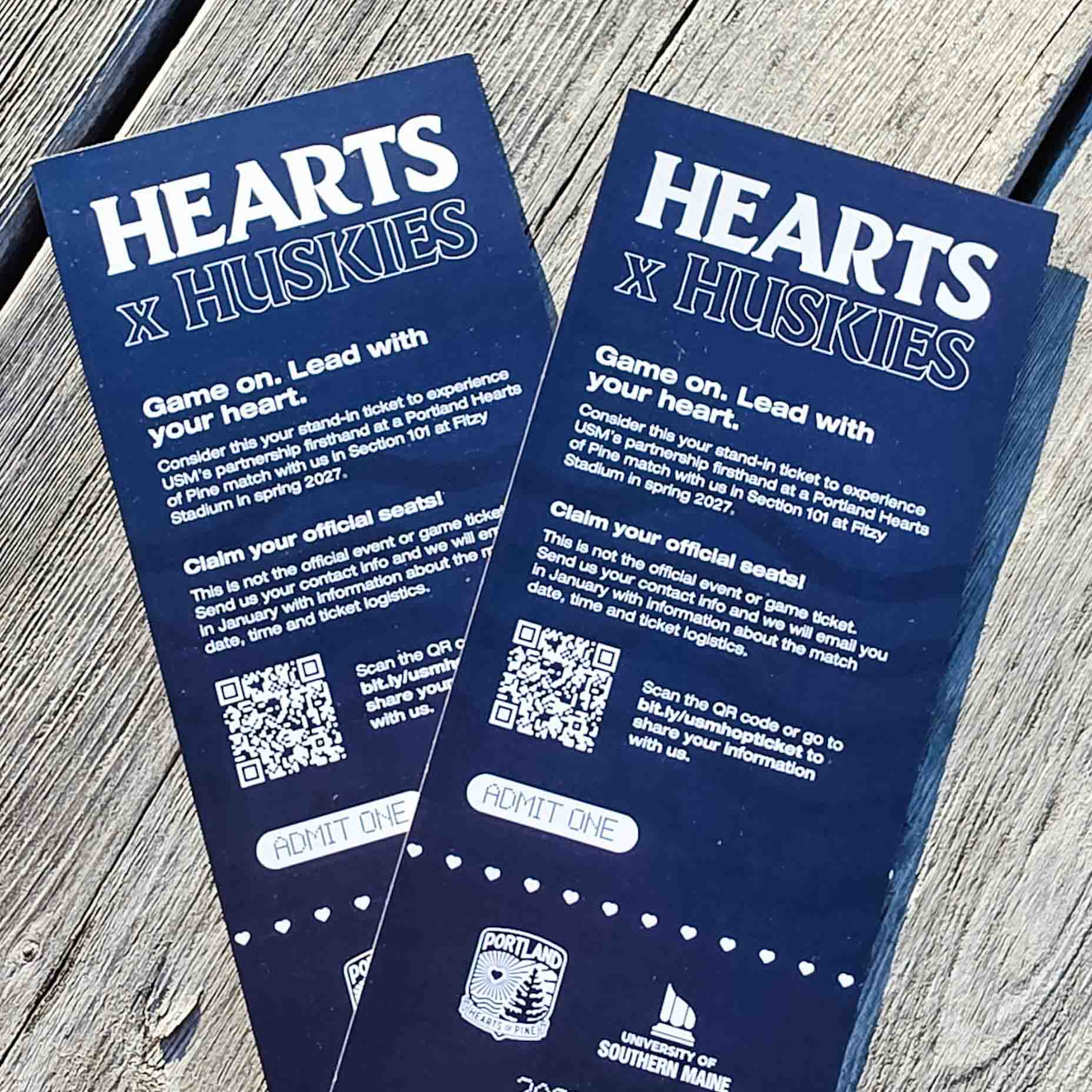 Two blue Hearts x Huskies stand-in tickets resting on wooden boards.