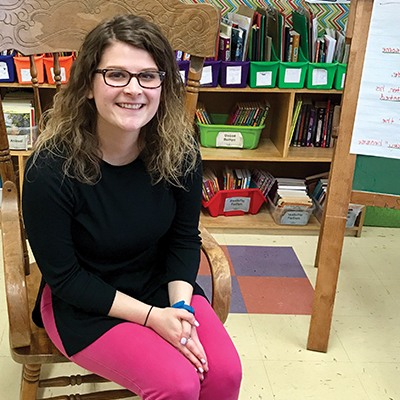 Elementary school teacher sits in chair in her classroom.