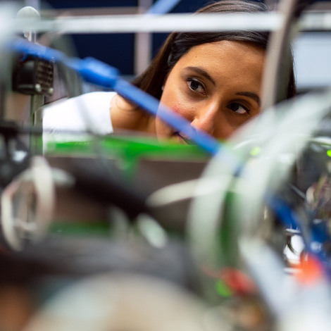 A student examining the wiring inside of a mechanical device