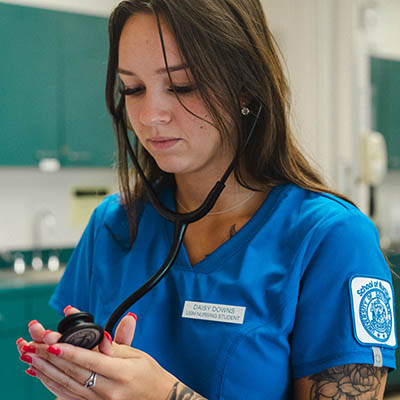 An accelerated nursing student at USM uses a stethoscope.