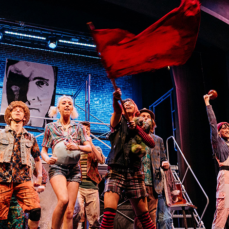 Students performing Urinetown and waving a red flag.