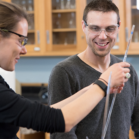 A faculty member demonstrates with chemistry instrumentation for a student.