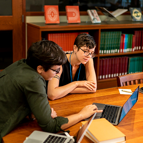 Two students study on a laptop together.