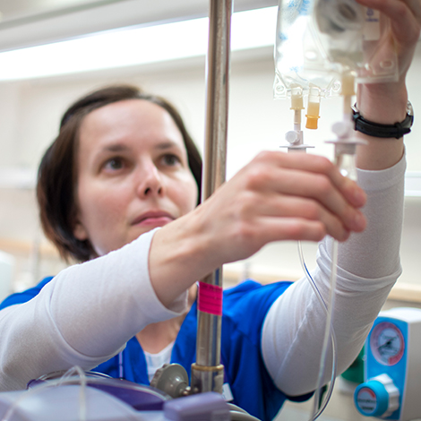 A nursing student checks an IV.