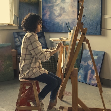 A student works on a painting in a studio.