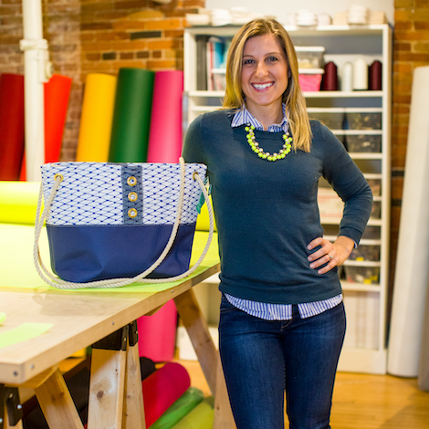 Alaina Marie, Founder of Bait Bags out of Portland Maine, stands next to one of her purses.