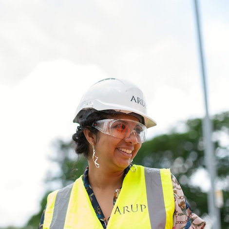 A student wearing safety gear surveys a project.