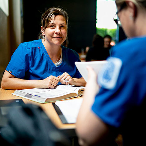A nursing student smiles while looking over a text book.