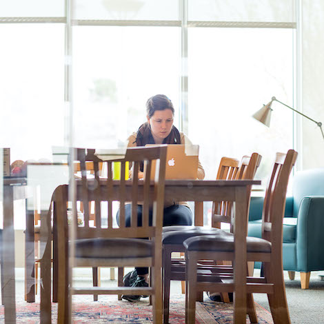 A student sitting a table in the library works on a computer.