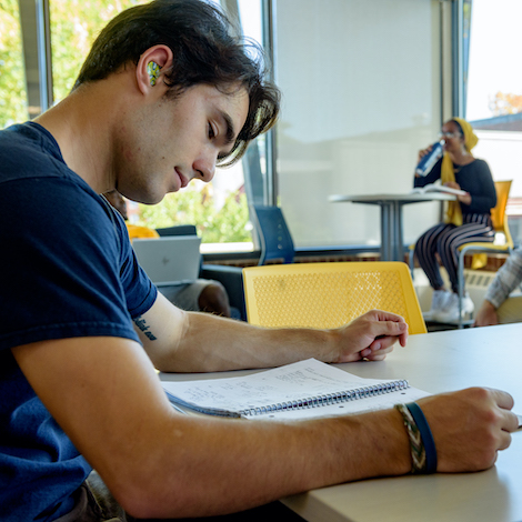 A student with hearing aids studies notes in a notebook.