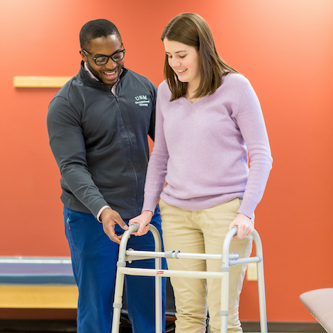 A student helps a patient with a mobility exercise.