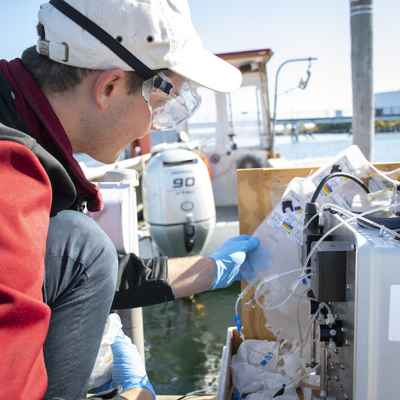 A biology student inspects equipment for an experiment on a boat.