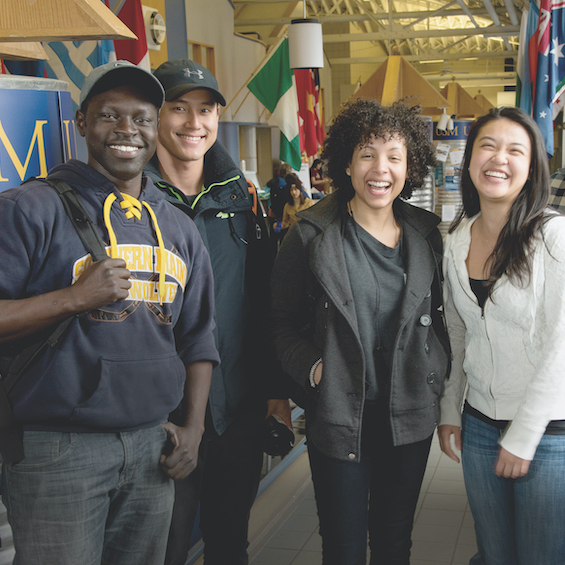 A group of students smile and laugh together at a campus cultural event.