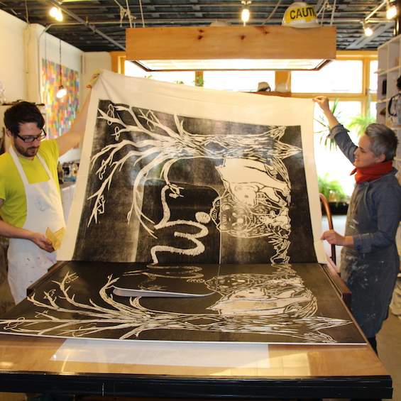 Two students work together on a large-scale art piece.