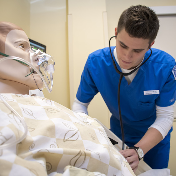 A nursing student practices a technique on a simulation mannequin.
