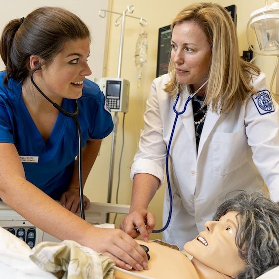 A nursing faculty member demonstrates a technique on a simulation mannequin.