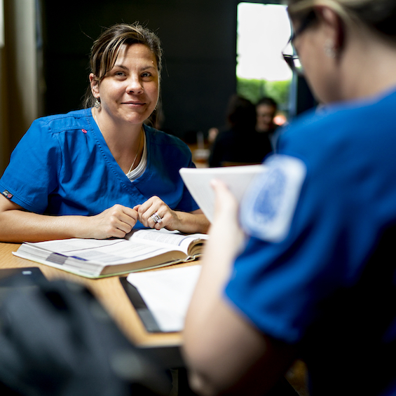 Two nursing students sit at a table and study.