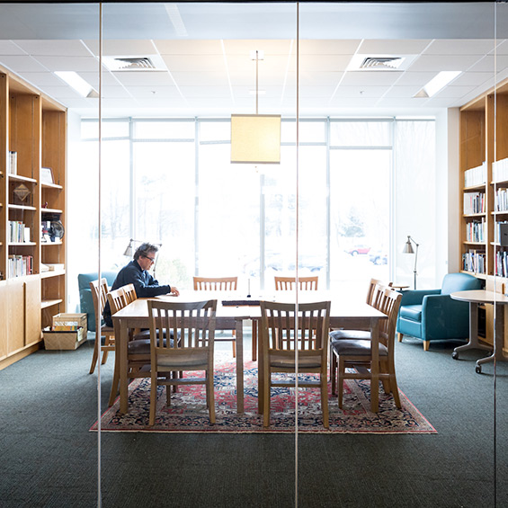 A student sits at a table in a small library room and reads.