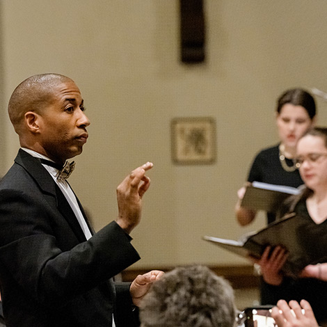 A faculty member conducts a group of singers.