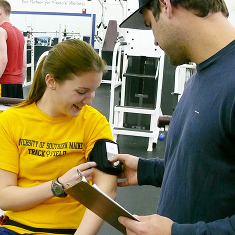 Students use a monitor on a woman's arm while she exercises.