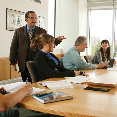 A faculty member walks around a table of seated students.