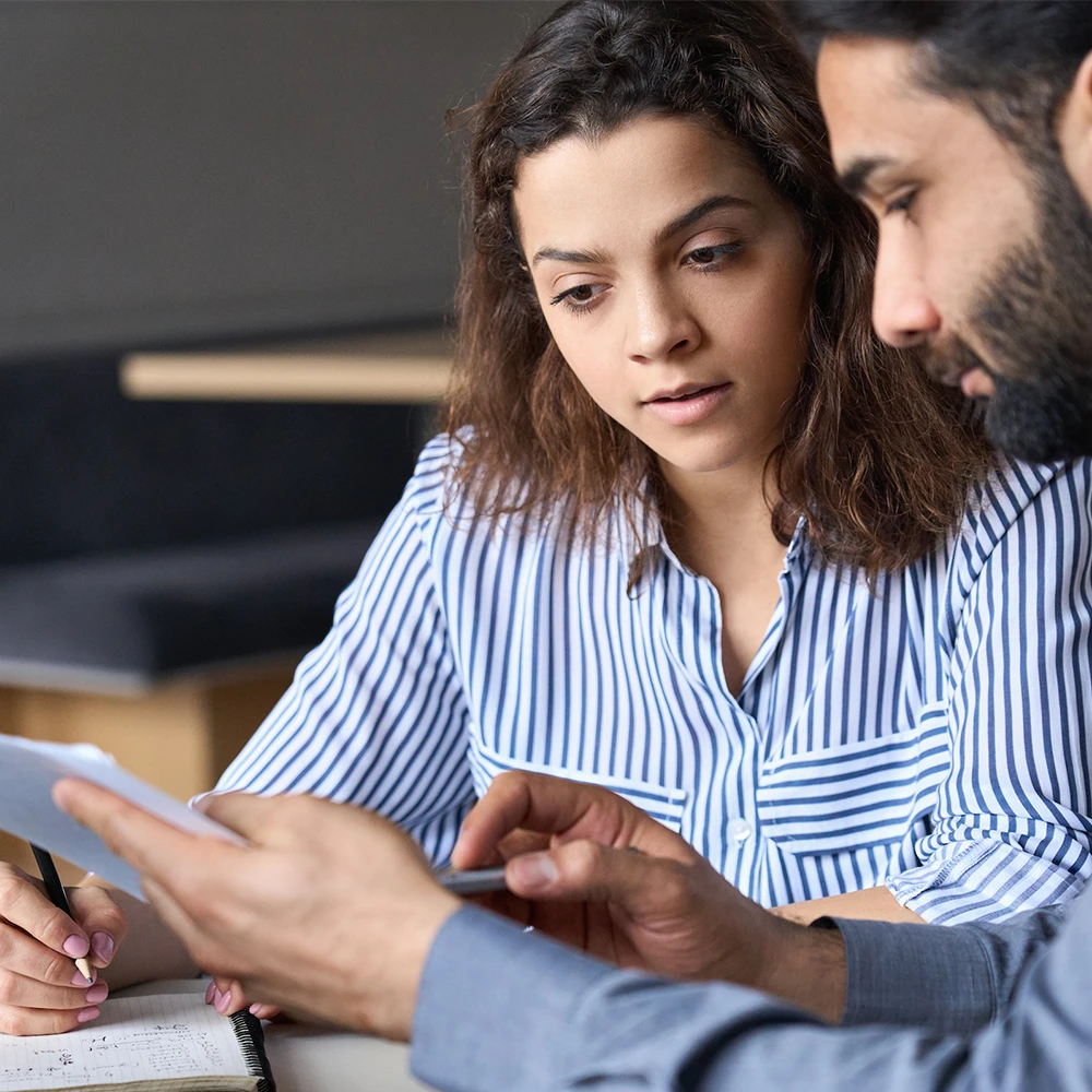 Two people sit and read a paper together.