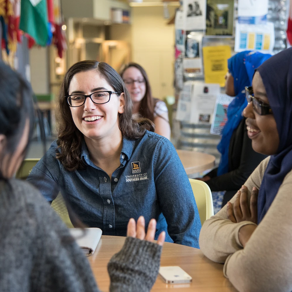 A USM staff member and student sit and chat with another student.