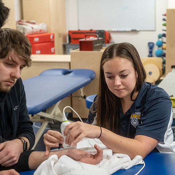 Students practice using ultrasound equipment on a student's arm.