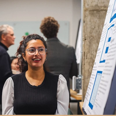 A student looking at a presentation with faculty behind her.