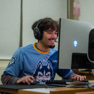 Esports player smiling in front of a computer.