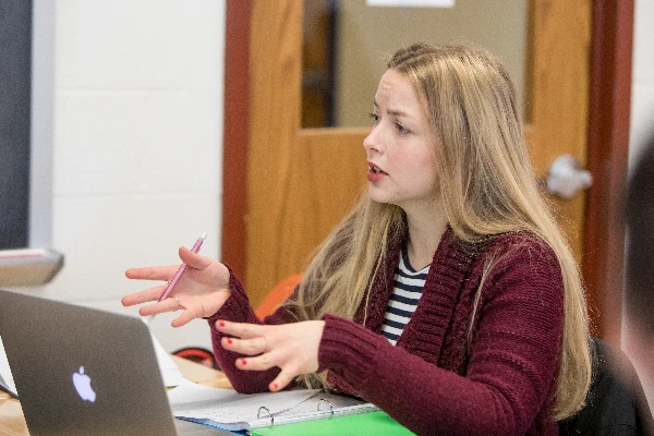 A person engaged in a discussion in front of a laptop.