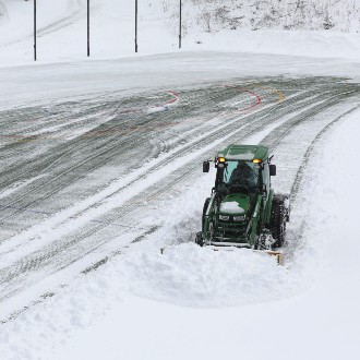 A plow driver works to remove five inches of snow from Hannaford Field before the home opener of the men's lacrosse season.