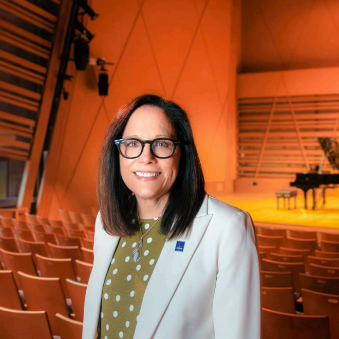 Photo Credit: Mainebiz. President Jacqueline poses for a headshot with the Crewe Performing Arts Stage behind her.