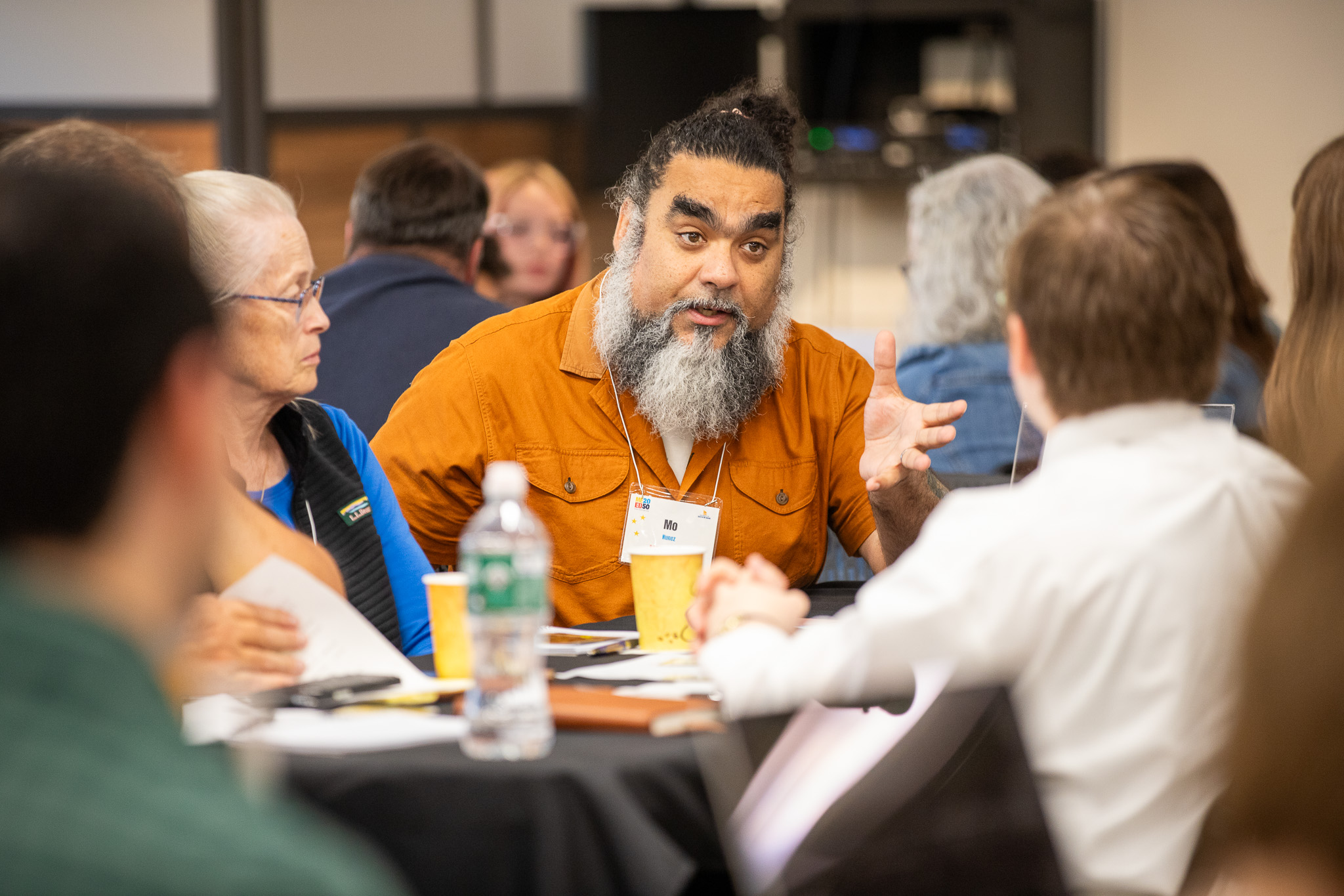 A delegate gestures while making a point during a table discussion.