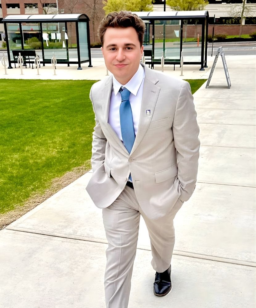 Maxfield Rhine walking on USM Portland campus in a gray suit.