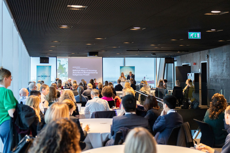 Attendees seated at tables in a conference room watching a presentation at the Arctic Circle Assembly