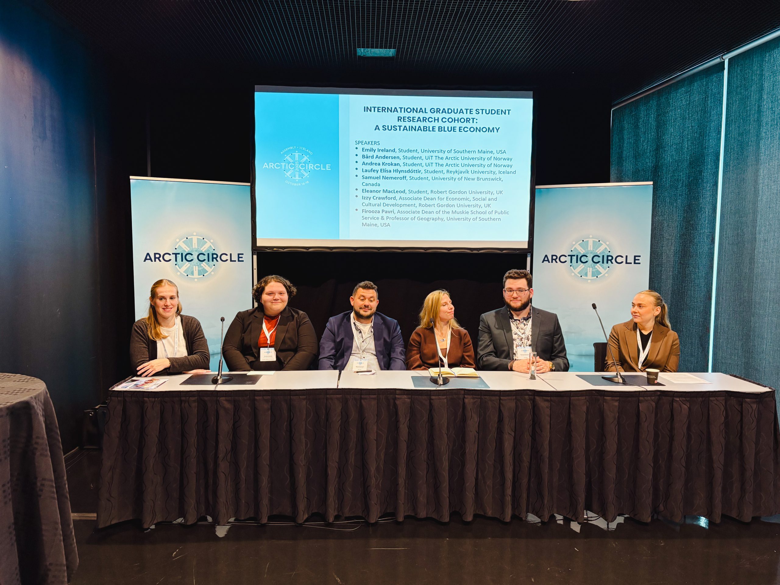 Emily Ireland and the rest of the graduate cohort sit at a table preparing for their presentations.