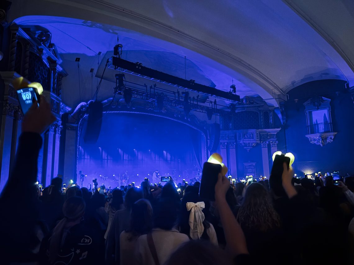 Concert at State Theatre in Portland, Maine with blue stage lights and audience holding up phone flashlights in the crowd