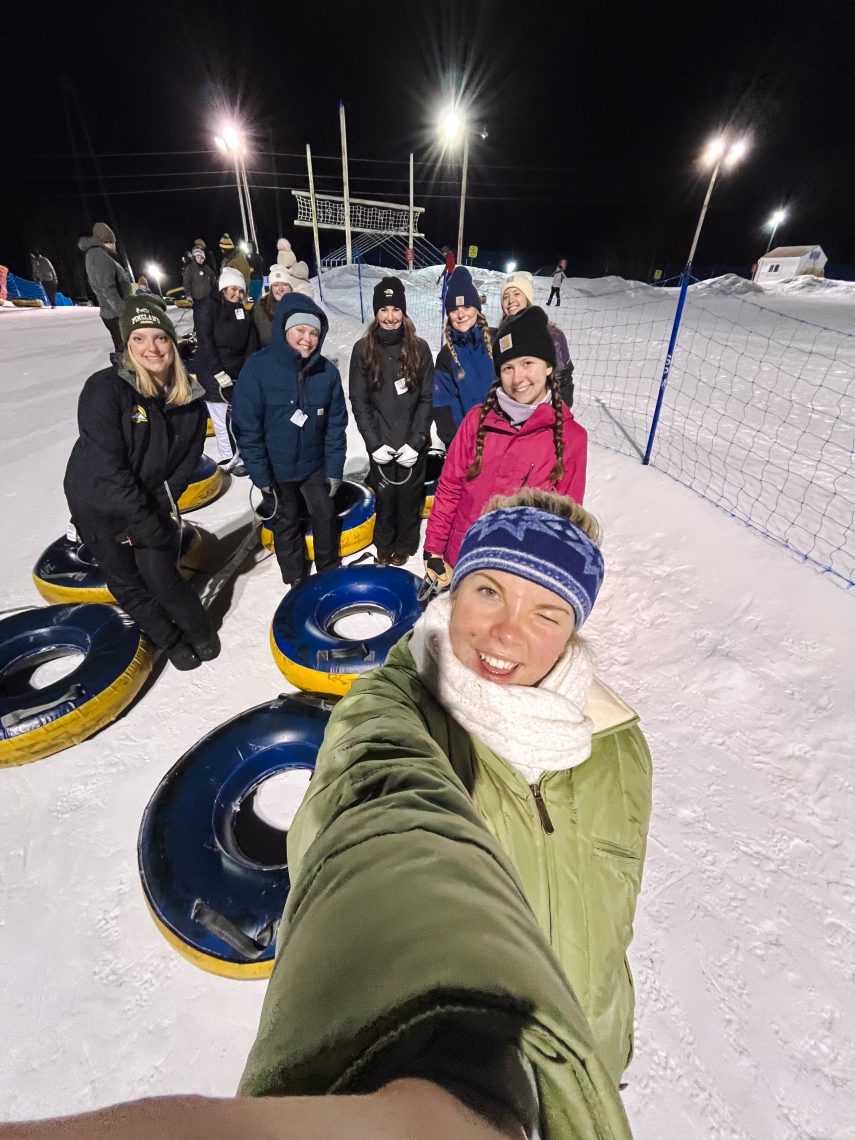 USM Outdoor Adventure Club students sledding down a snowy hill together in Southern Maine in winter.