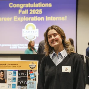 Karoline Brechter stands next to her internship presentation poster at the Career Hub exhibition