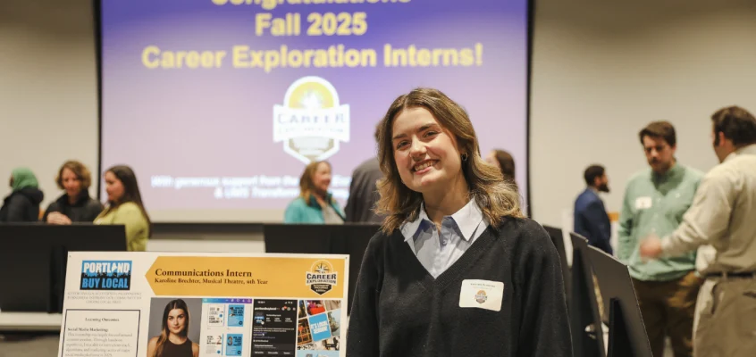 Karoline Brechter stands next to her internship presentation poster at the Career Hub exhibition