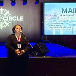 Emily Ireland delivers a speech at a microphone at the Maine luncheon during the Arctic Circle Assembly.