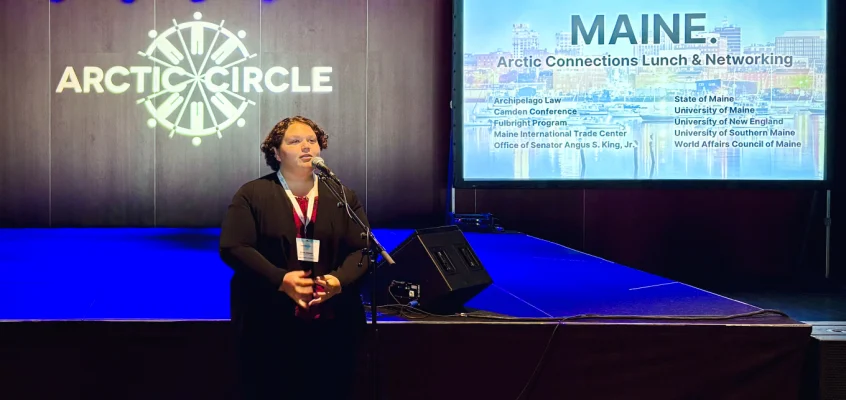 Emily Ireland delivers a speech at a microphone at the Maine luncheon during the Arctic Circle Assembly.