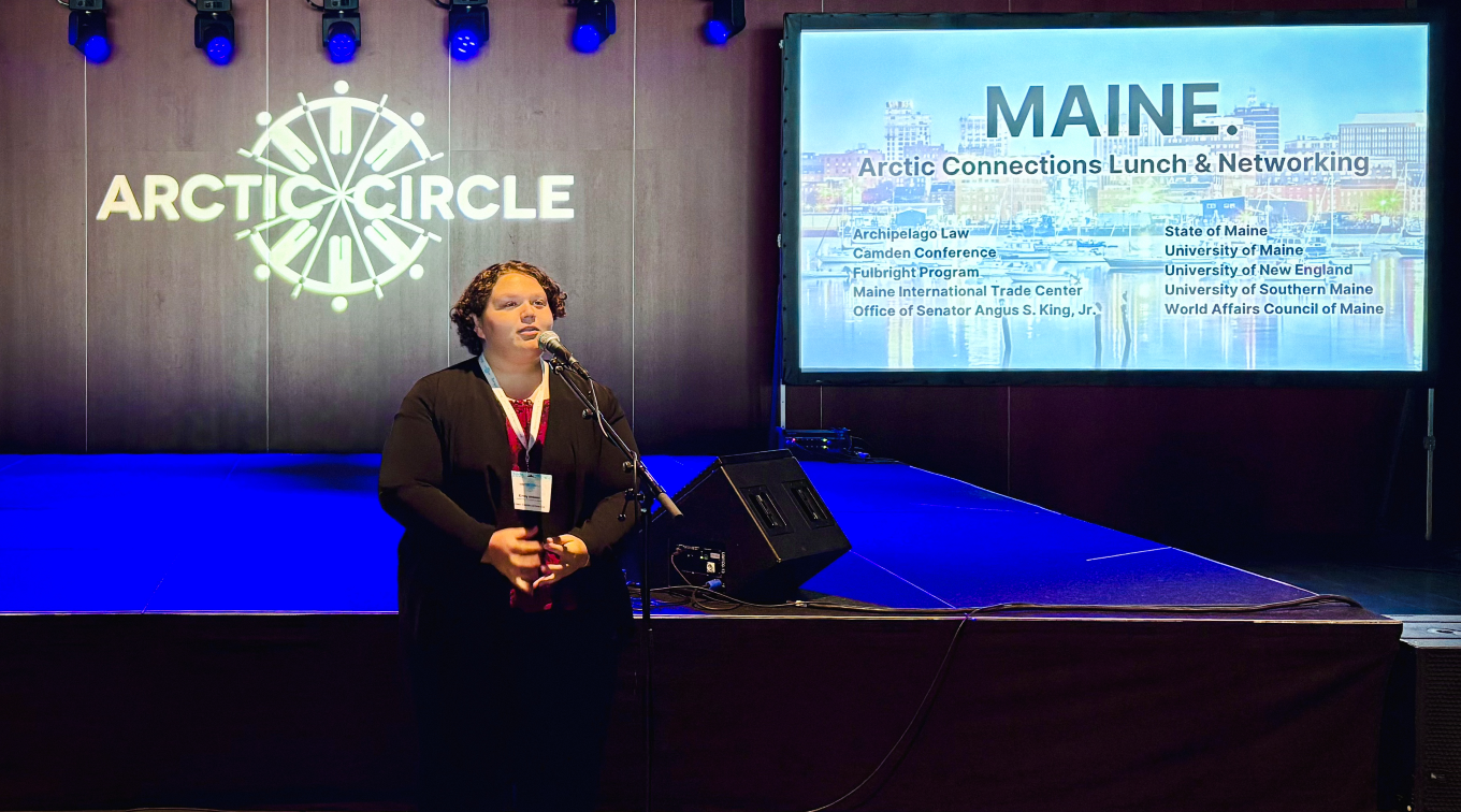 Emily Ireland delivers a speech at a microphone at the Maine luncheon during the Arctic Circle Assembly.