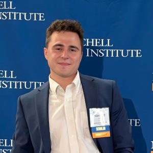 Maxfield Rhine standing in front of Mitchell Institute step and repeat.