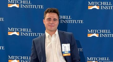 Maxfield Rhine standing in front of Mitchell Institute step and repeat.