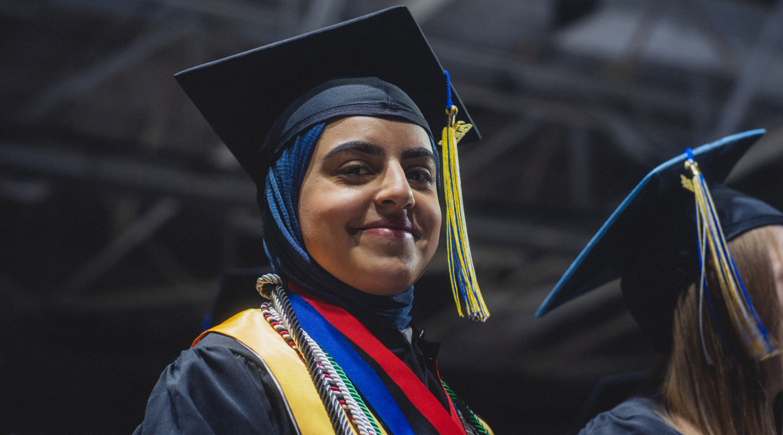 A USM Student in full commencement regalia smiling proudly during commencement.