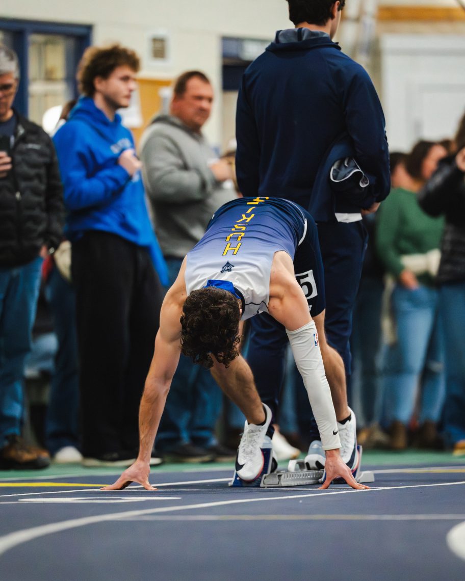 USM student Maddox Cahill in the starting blocks, bent over at the start of a track race, ready to sprint.